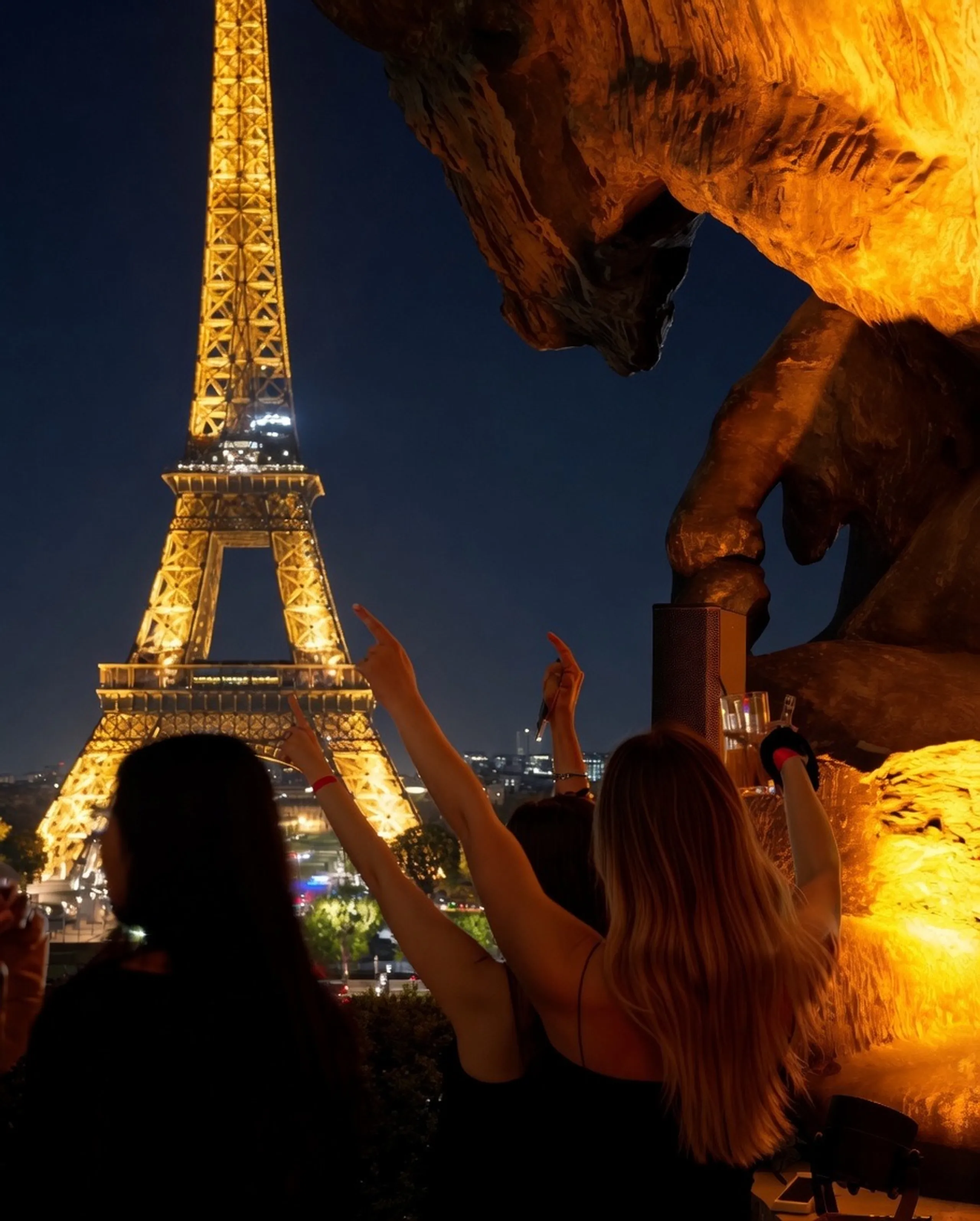 Des convives lèvent les bras face à la tour Eiffel scintillante