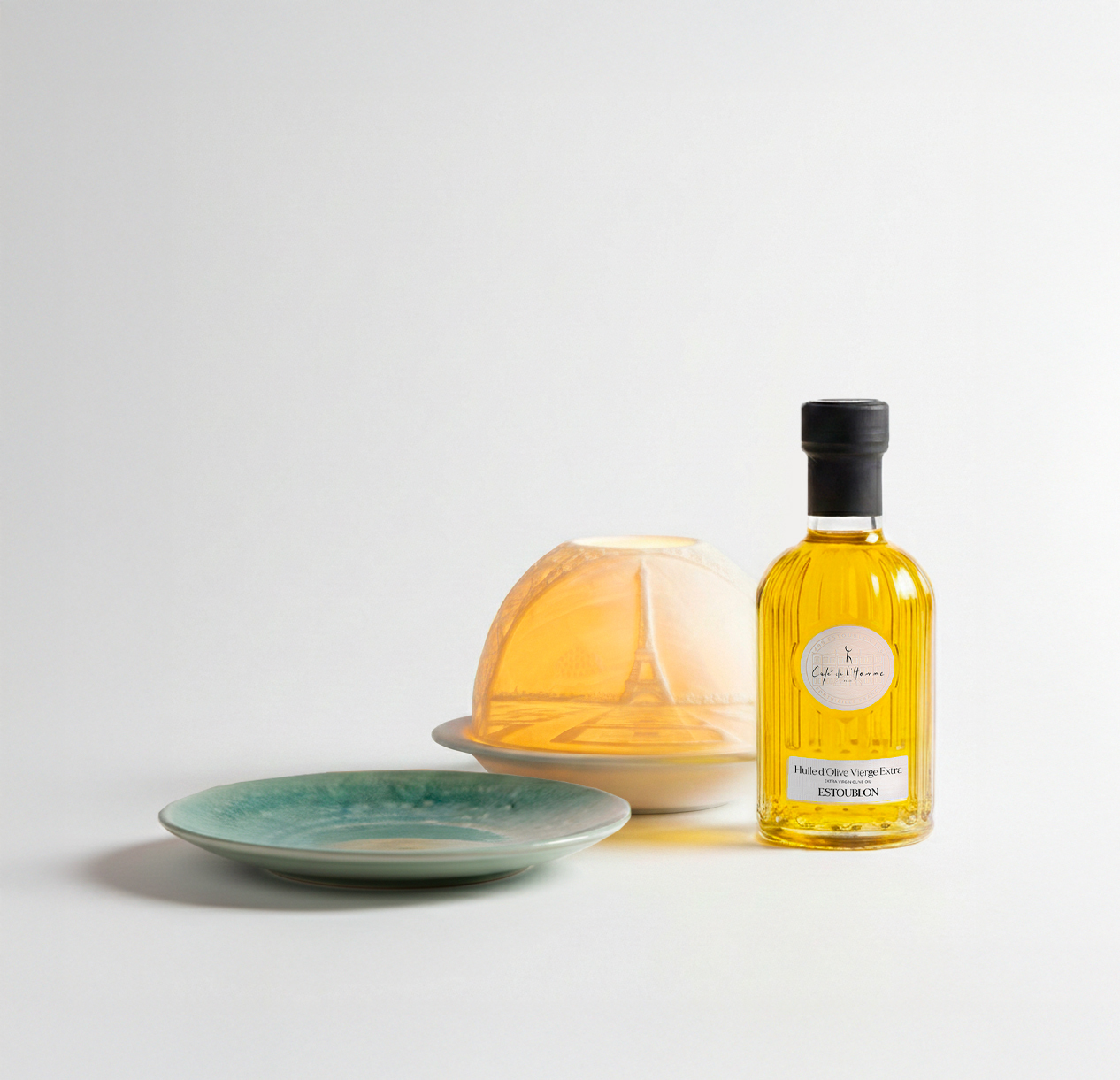A composition of Café de l'Homme signature products: cloche, plate and olive oil